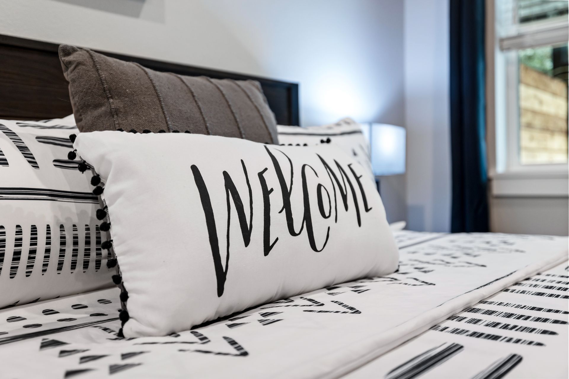 A bed with a pillow that says welcome on it