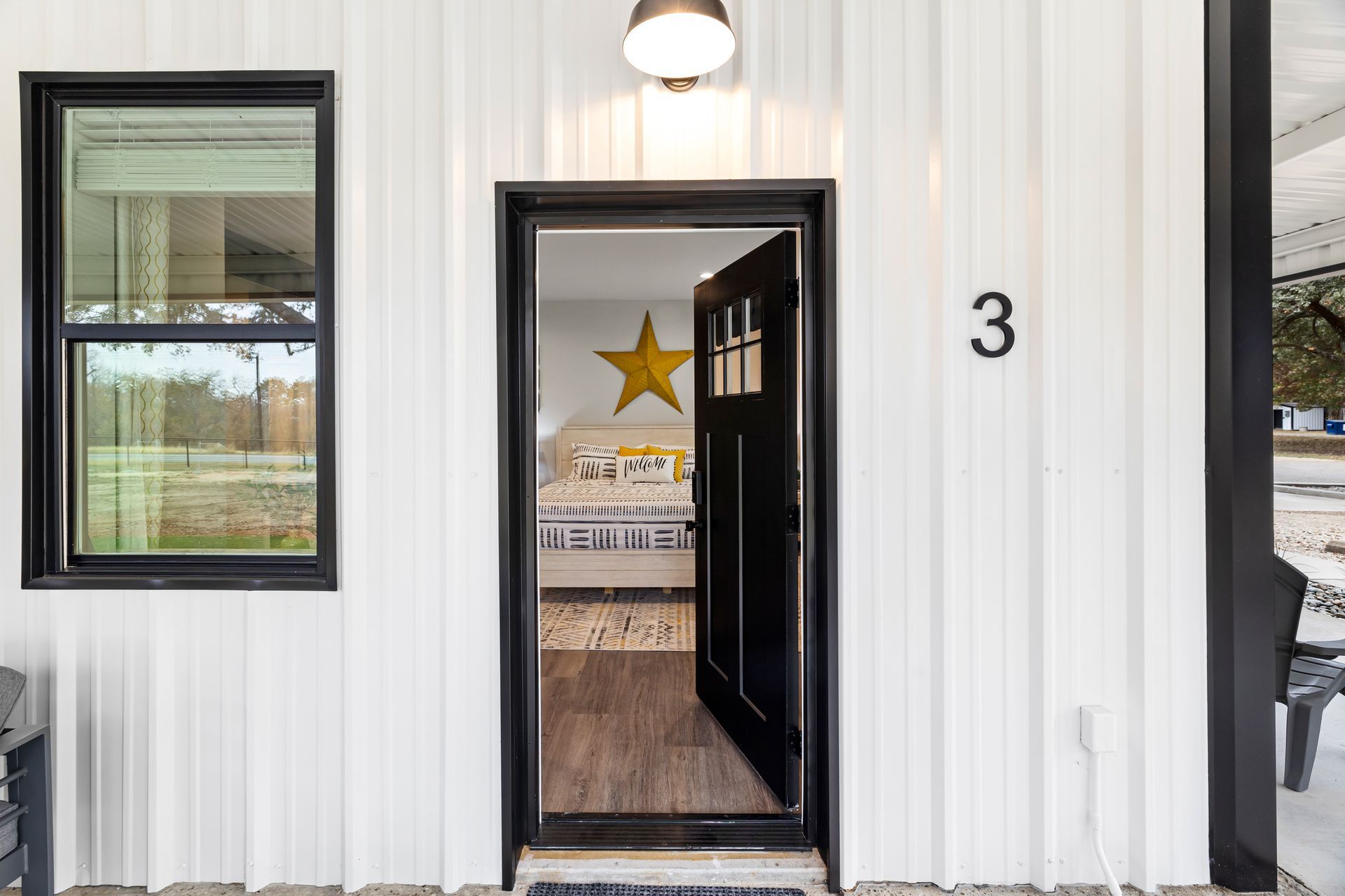 The front door of a white house with a black door and a star on it.