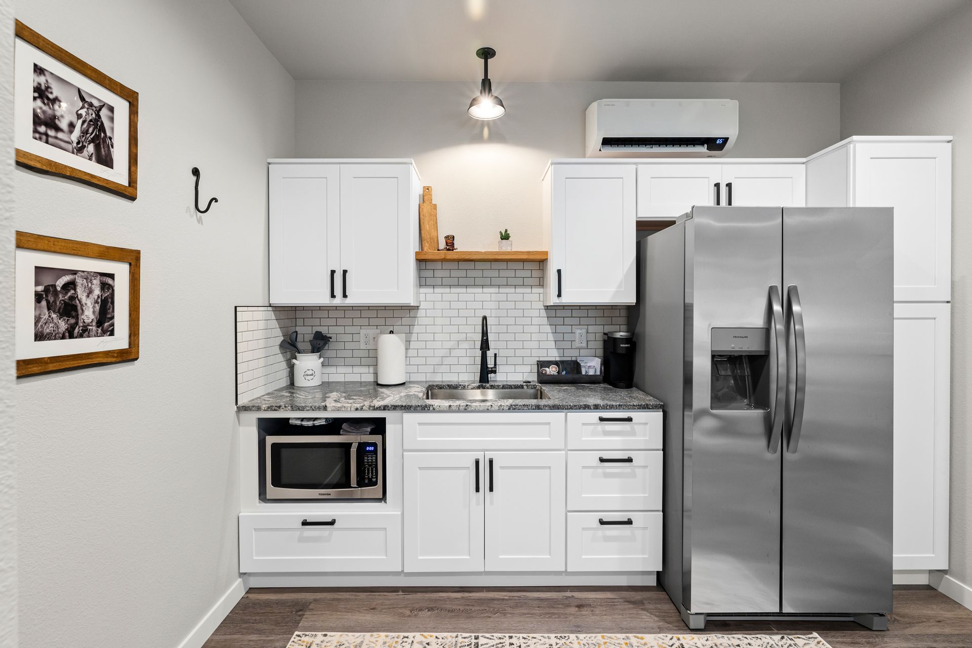 A kitchen with white cabinets , a stainless steel refrigerator , a microwave , and a sink.