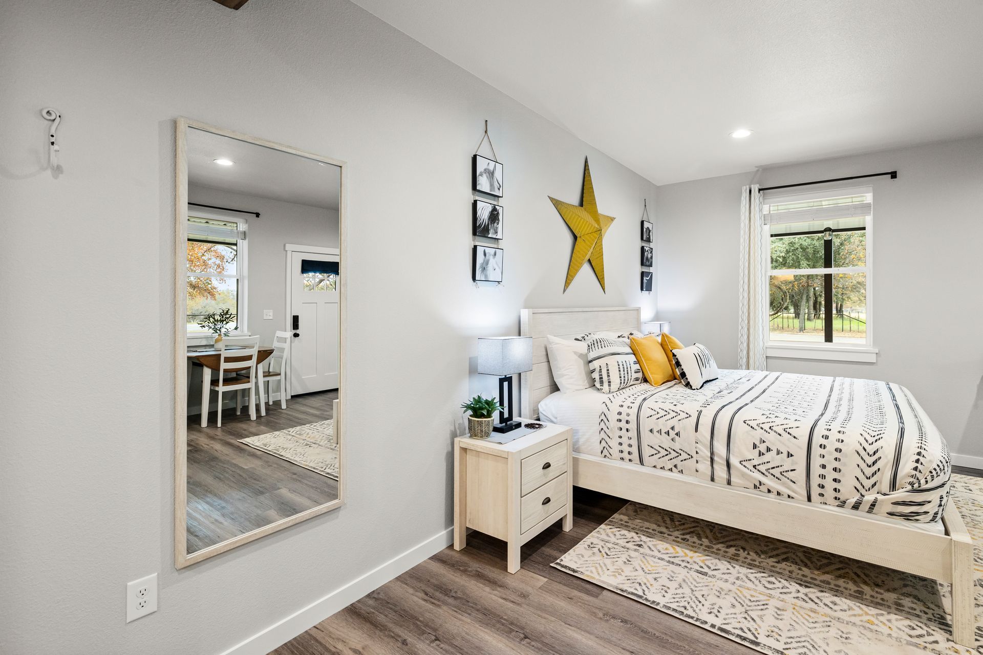 A bedroom with a bed , nightstand , mirror and star on the wall.