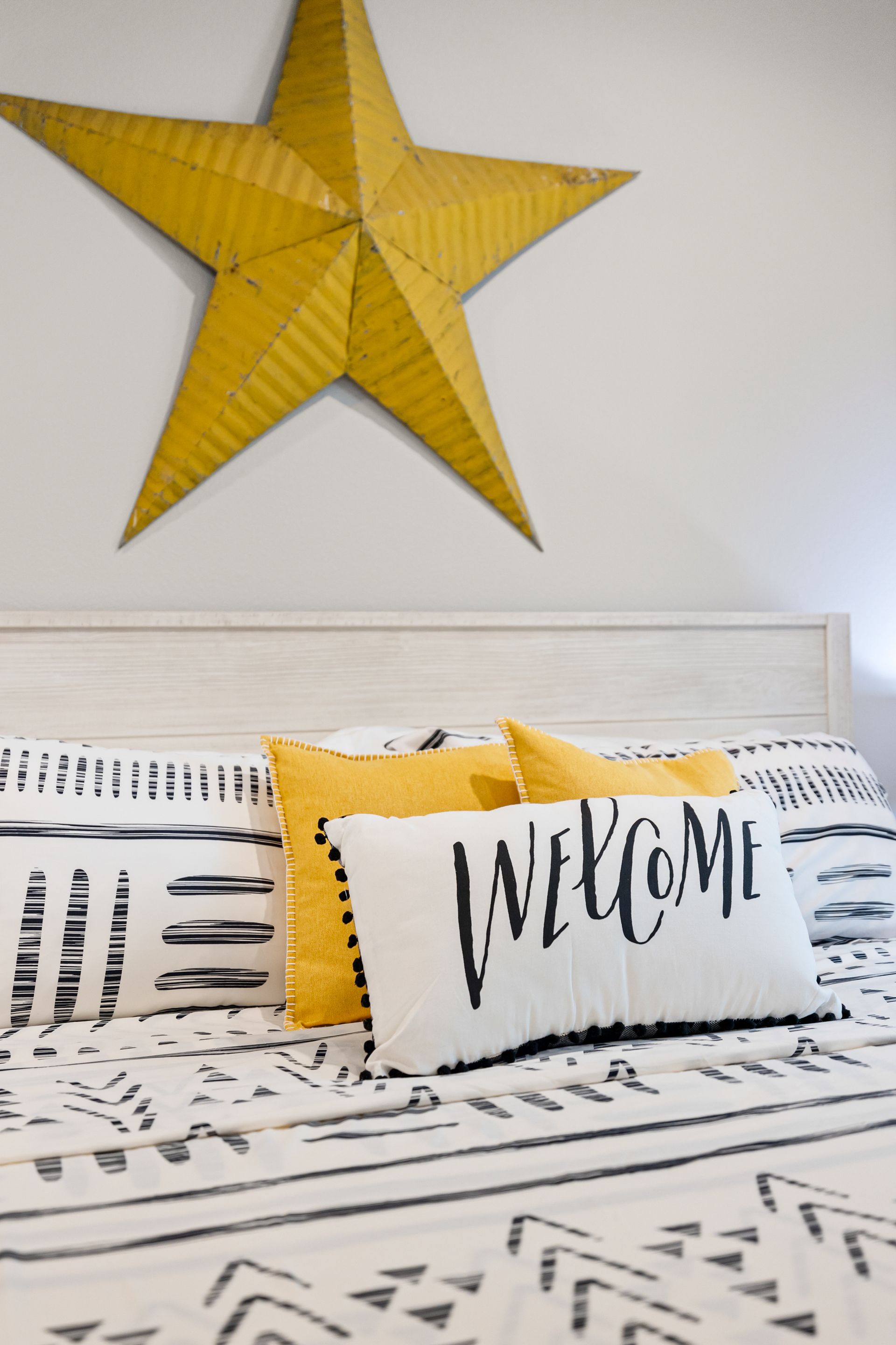 A bed with a yellow star above it and a welcome pillow