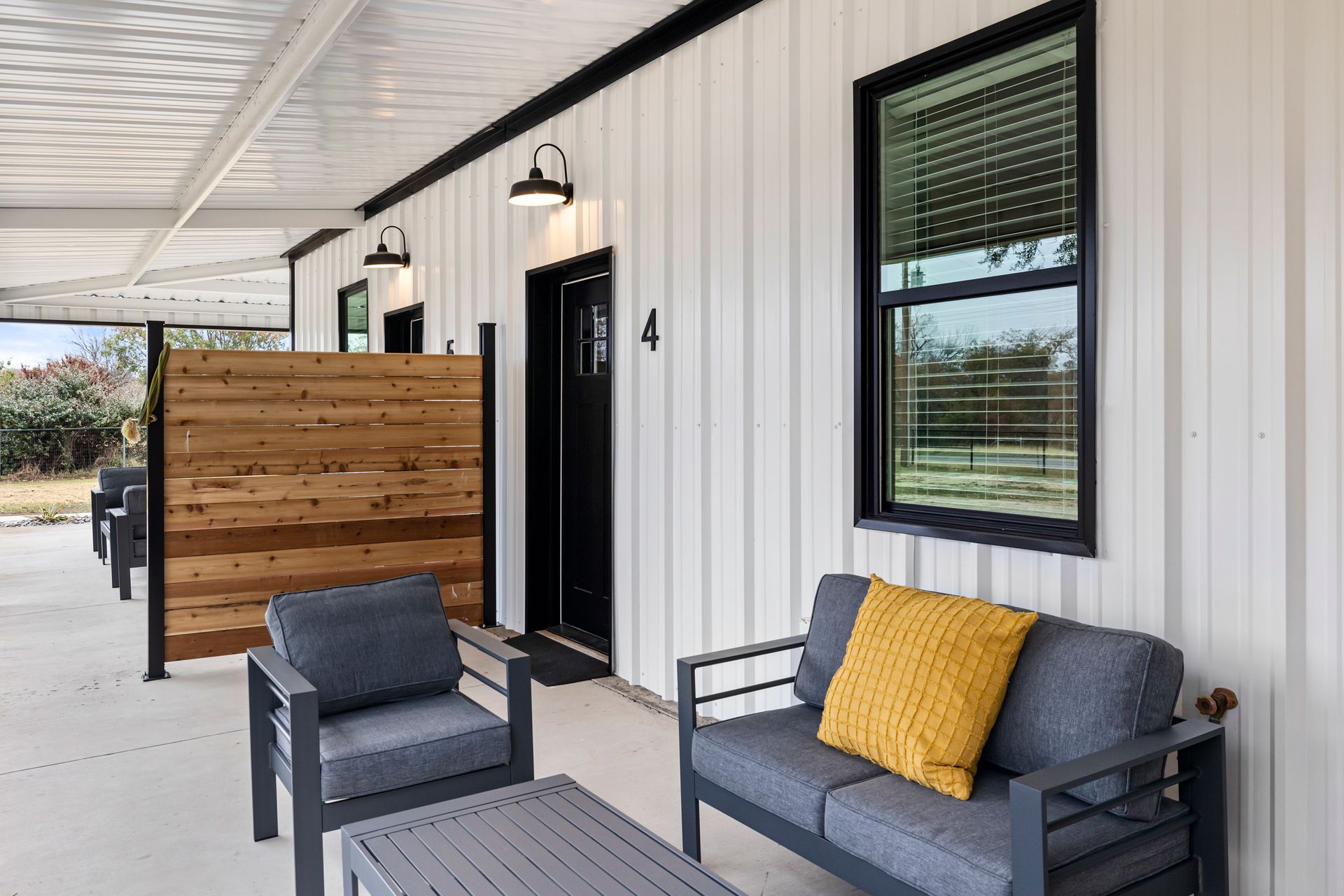 There is a couch and chairs on the porch of a house.