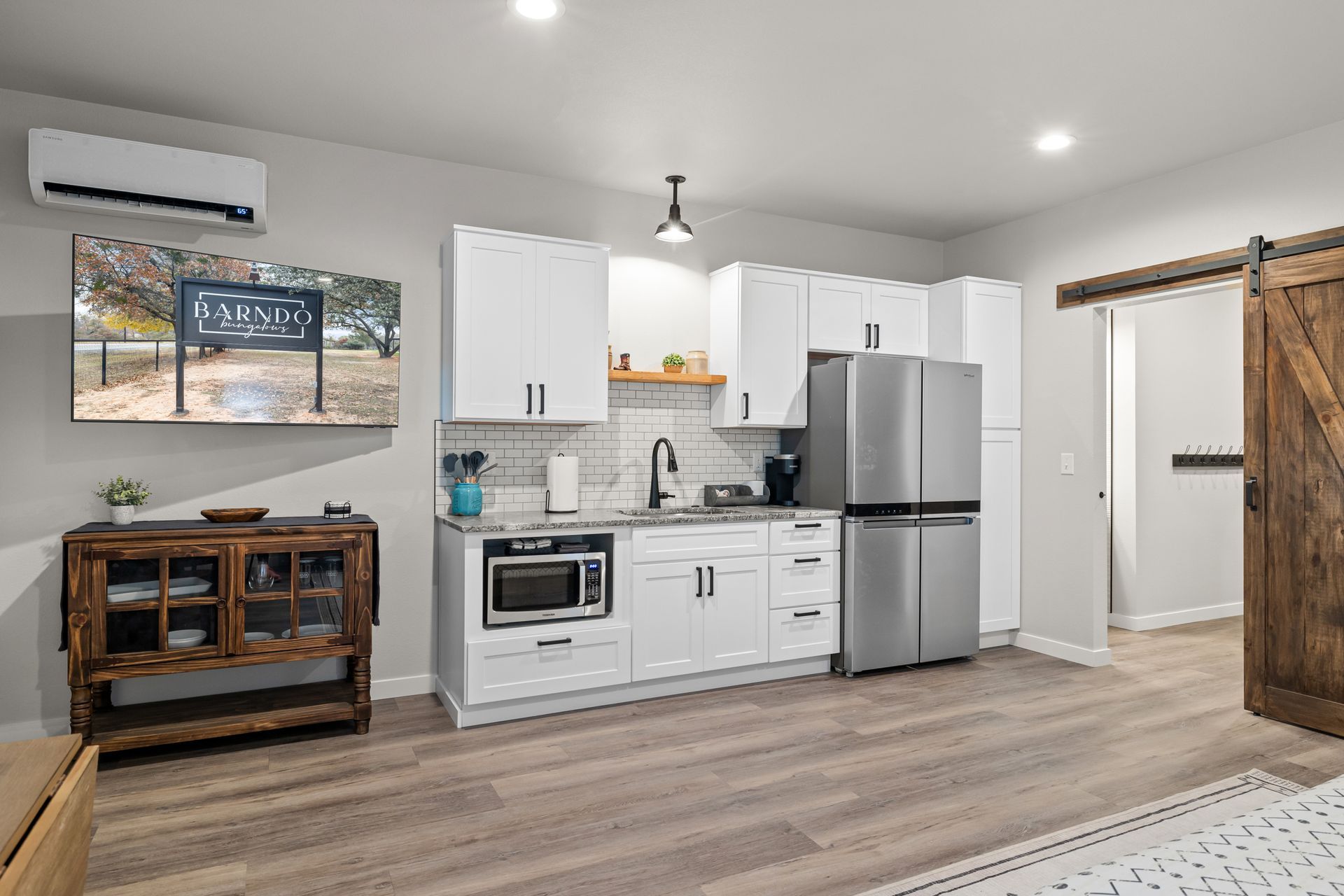 A kitchen with white cabinets , stainless steel appliances , a refrigerator and a microwave.