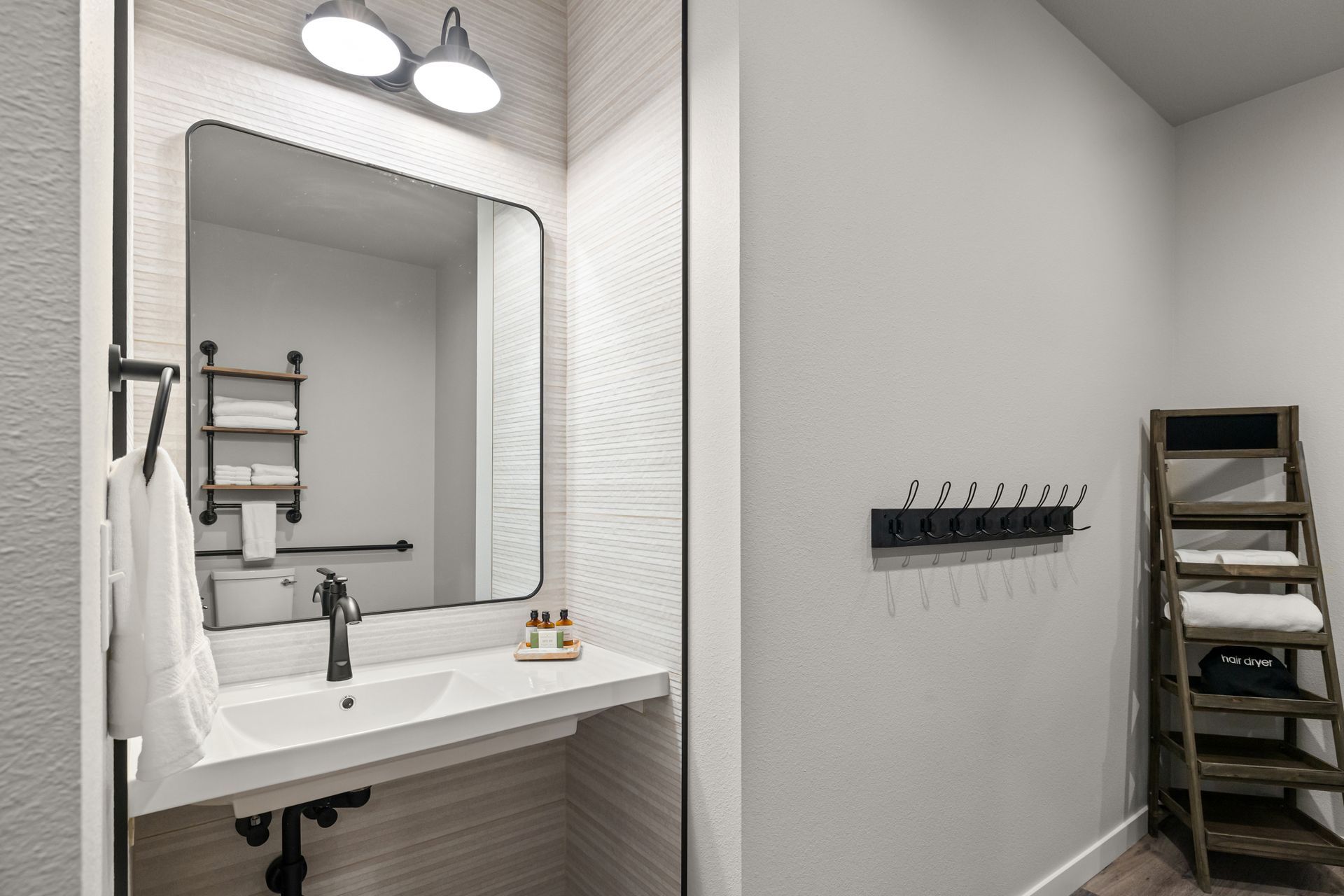A bathroom with a sink , mirror and towel rack.