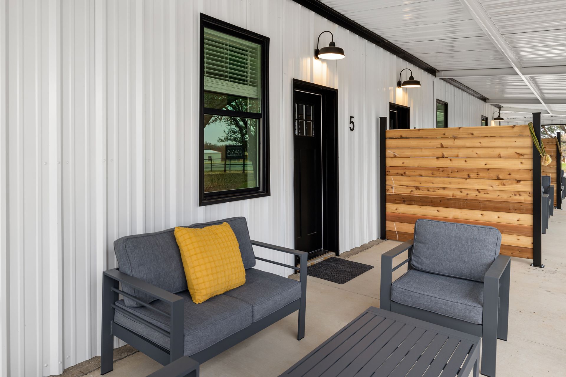 There is a couch and chair on the porch of a building.