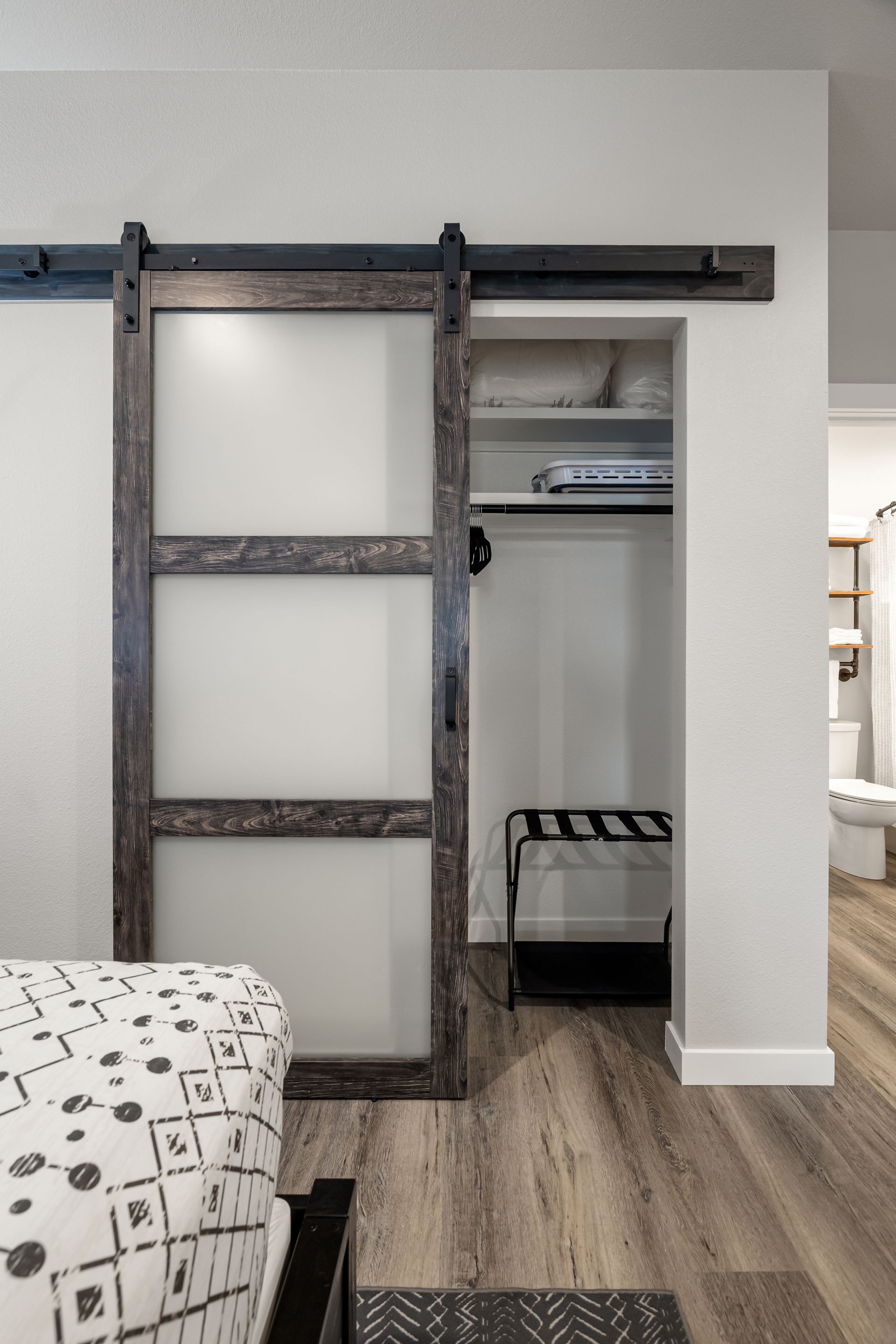 A bedroom with a sliding barn door leading to a closet.