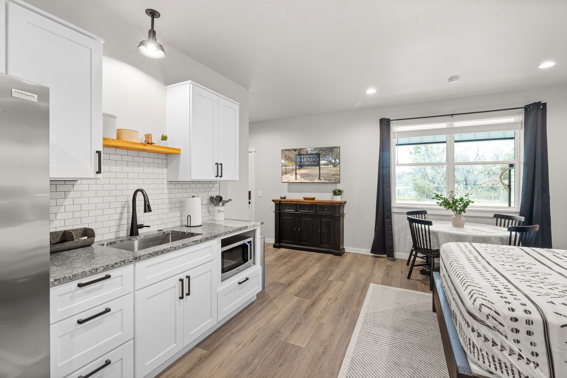 A kitchen with white cabinets , granite counter tops , stainless steel appliances , a refrigerator and a sink.
