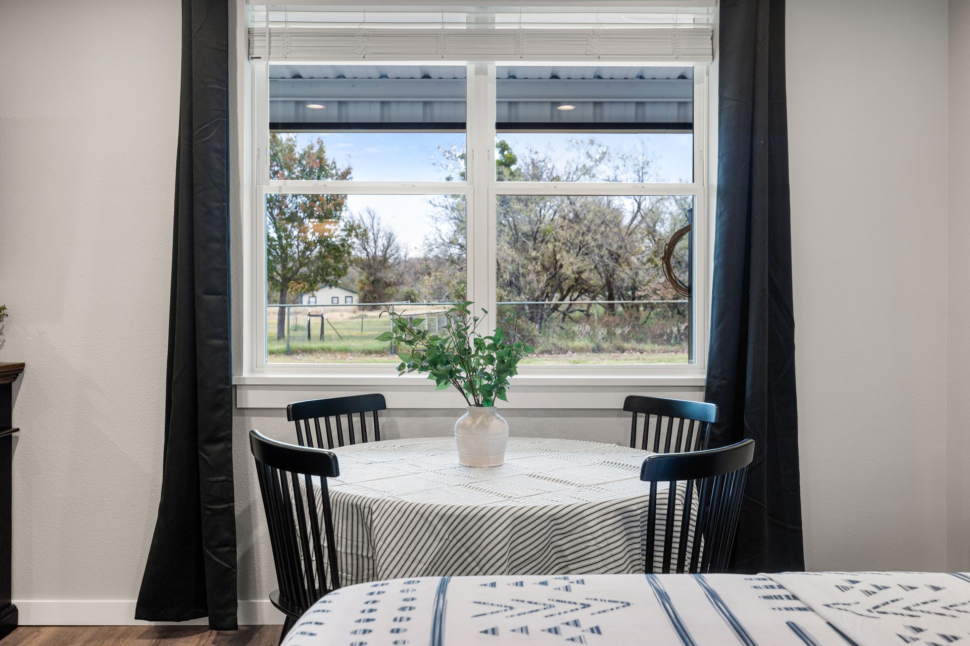 A dining room with a table and chairs in front of a window.
