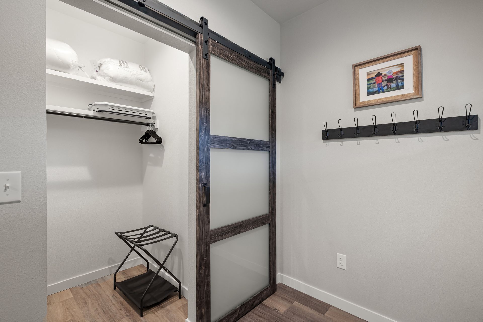 A closet with a sliding barn door and a picture on the wall.