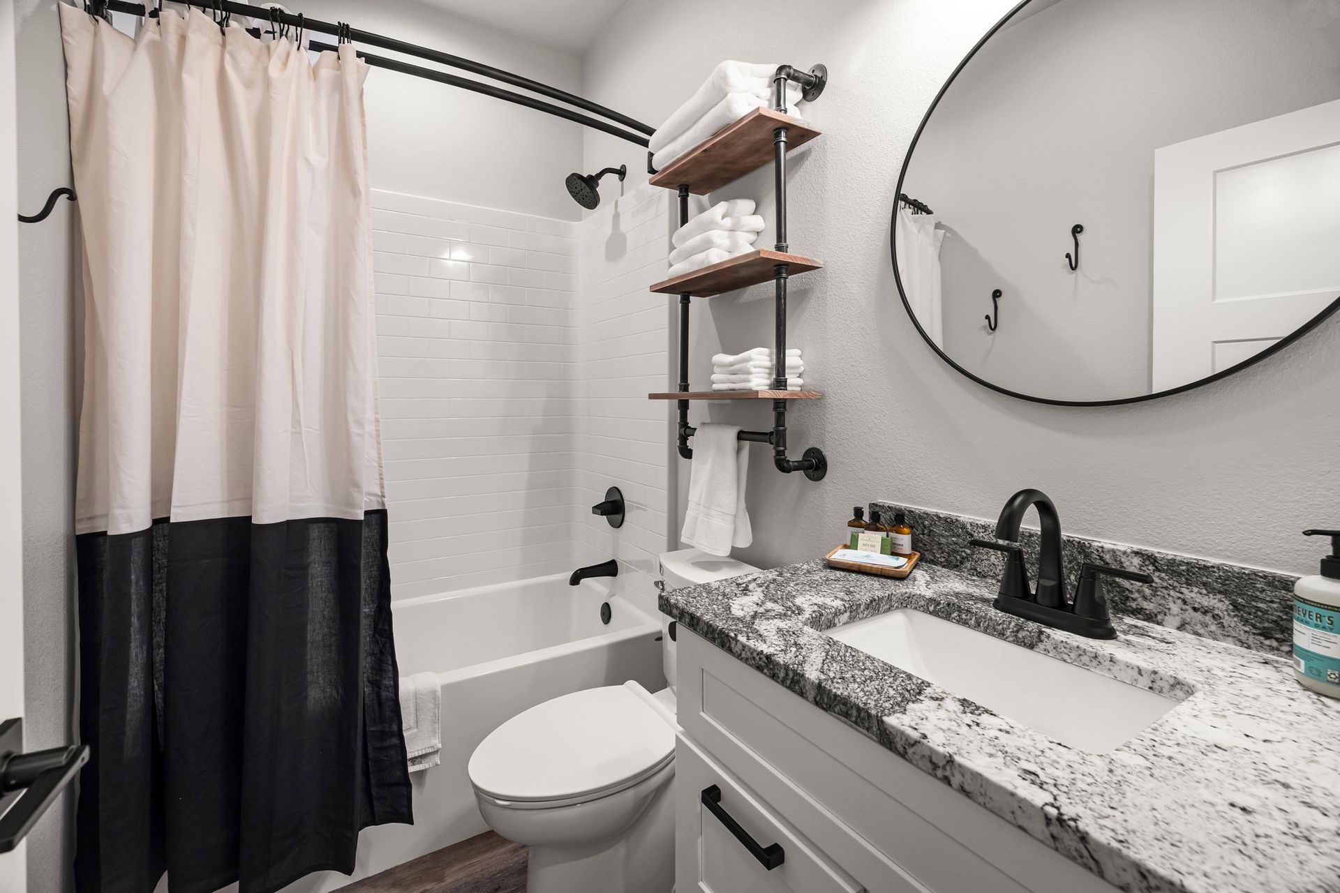 A bathroom with a toilet , sink , shower and mirror.