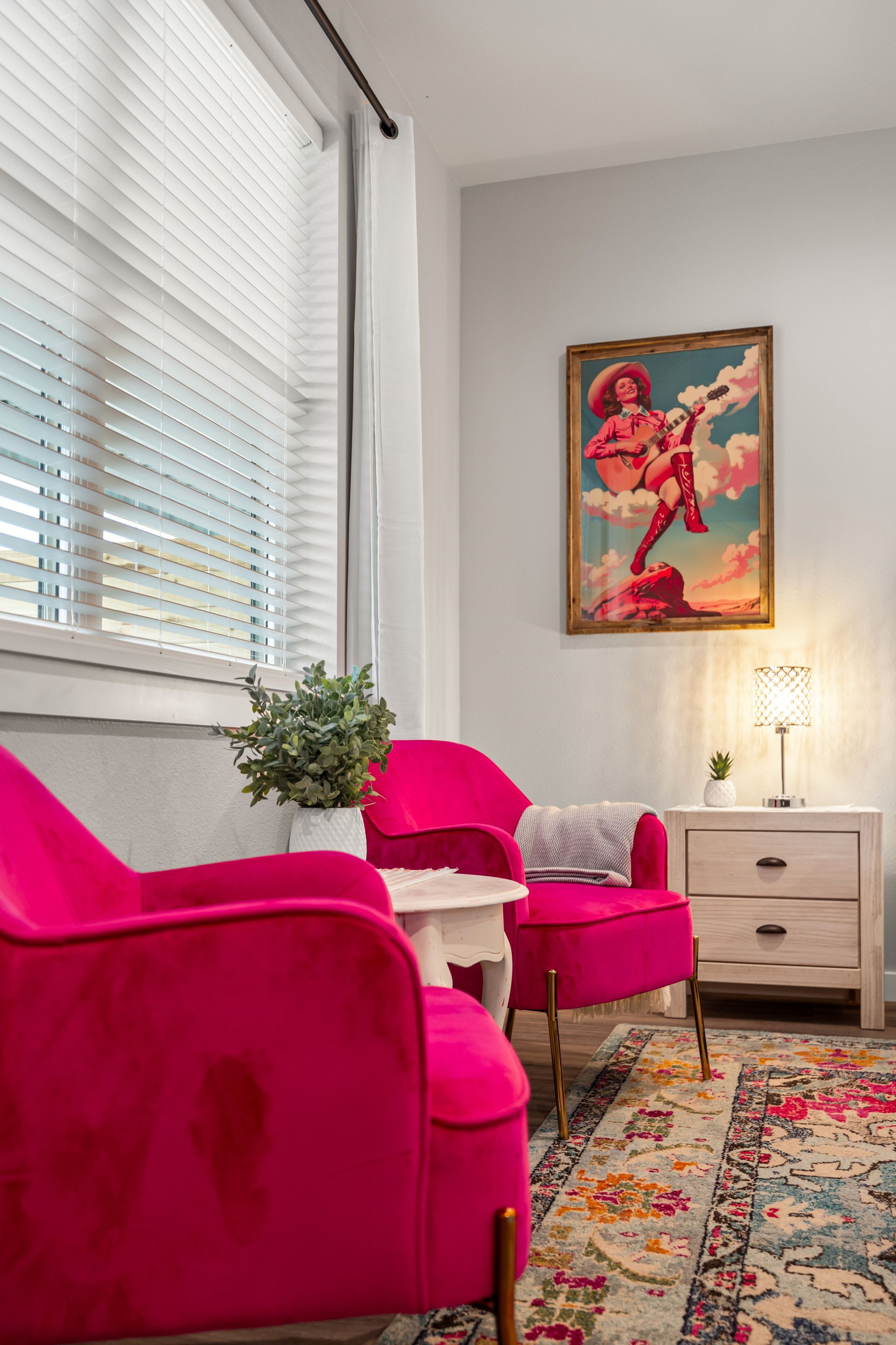 A living room with two pink chairs and a painting on the wall.