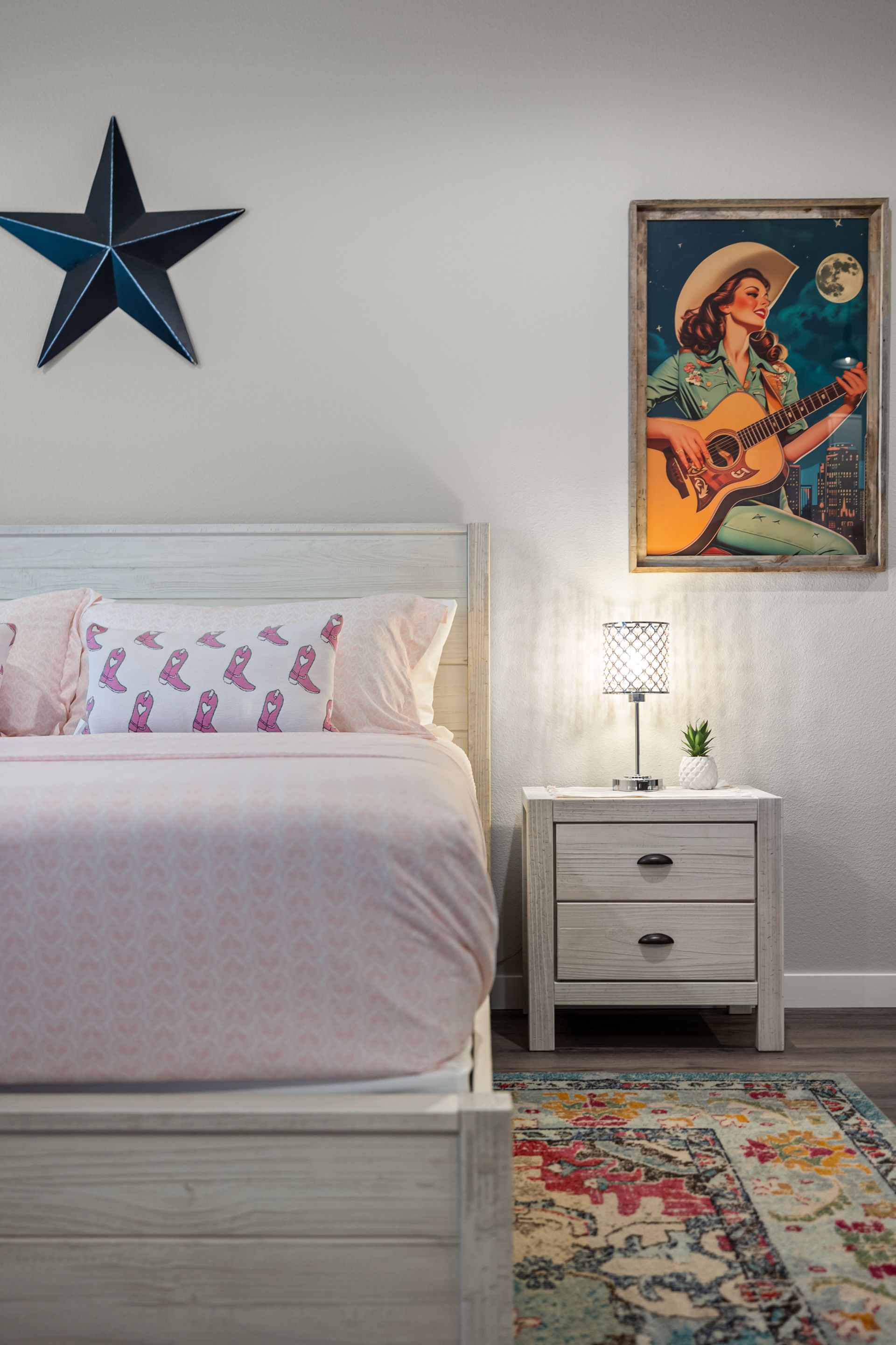 There is a painting of a woman playing a guitar on the wall above the bed.