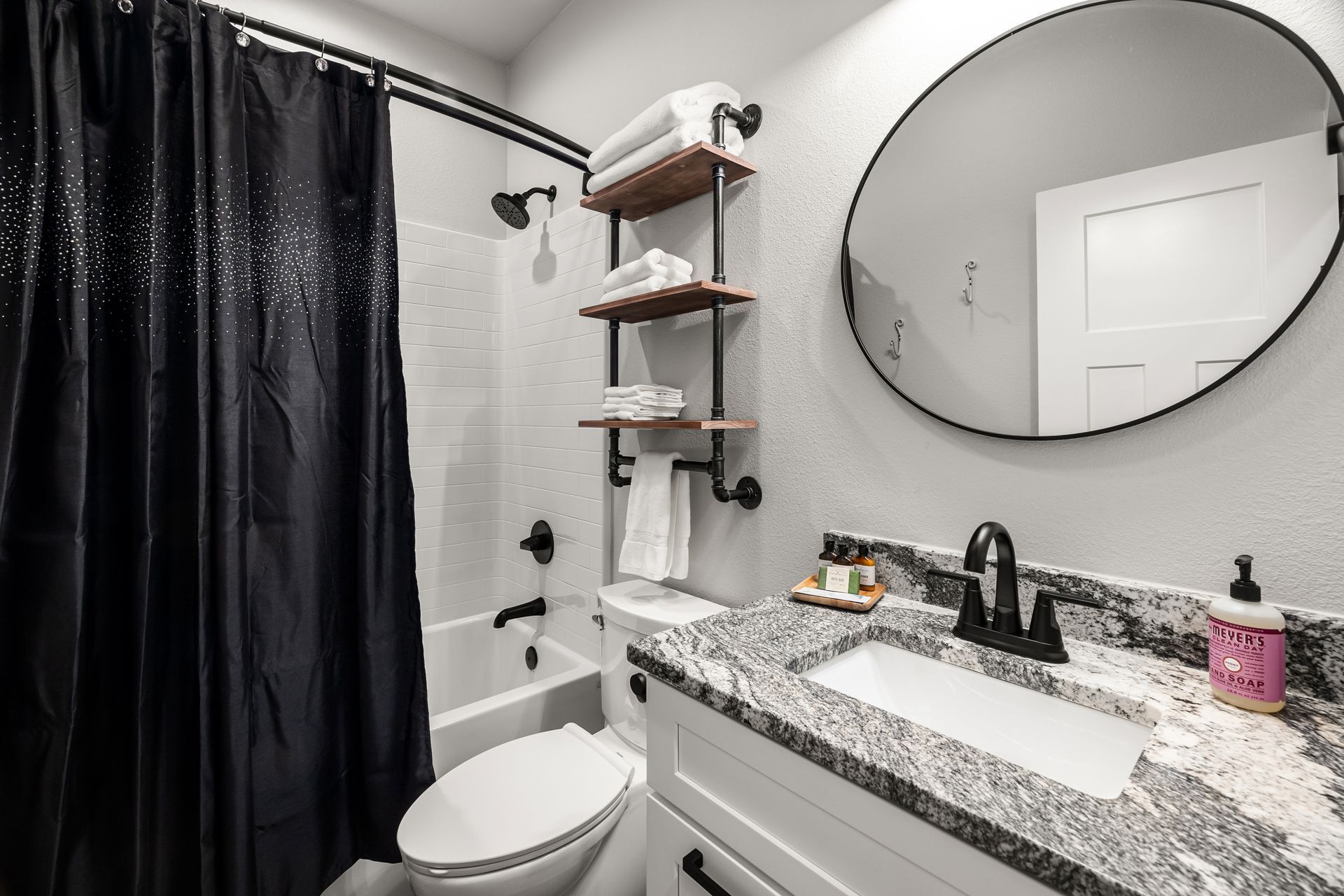 A bathroom with a toilet , sink , shower and mirror.