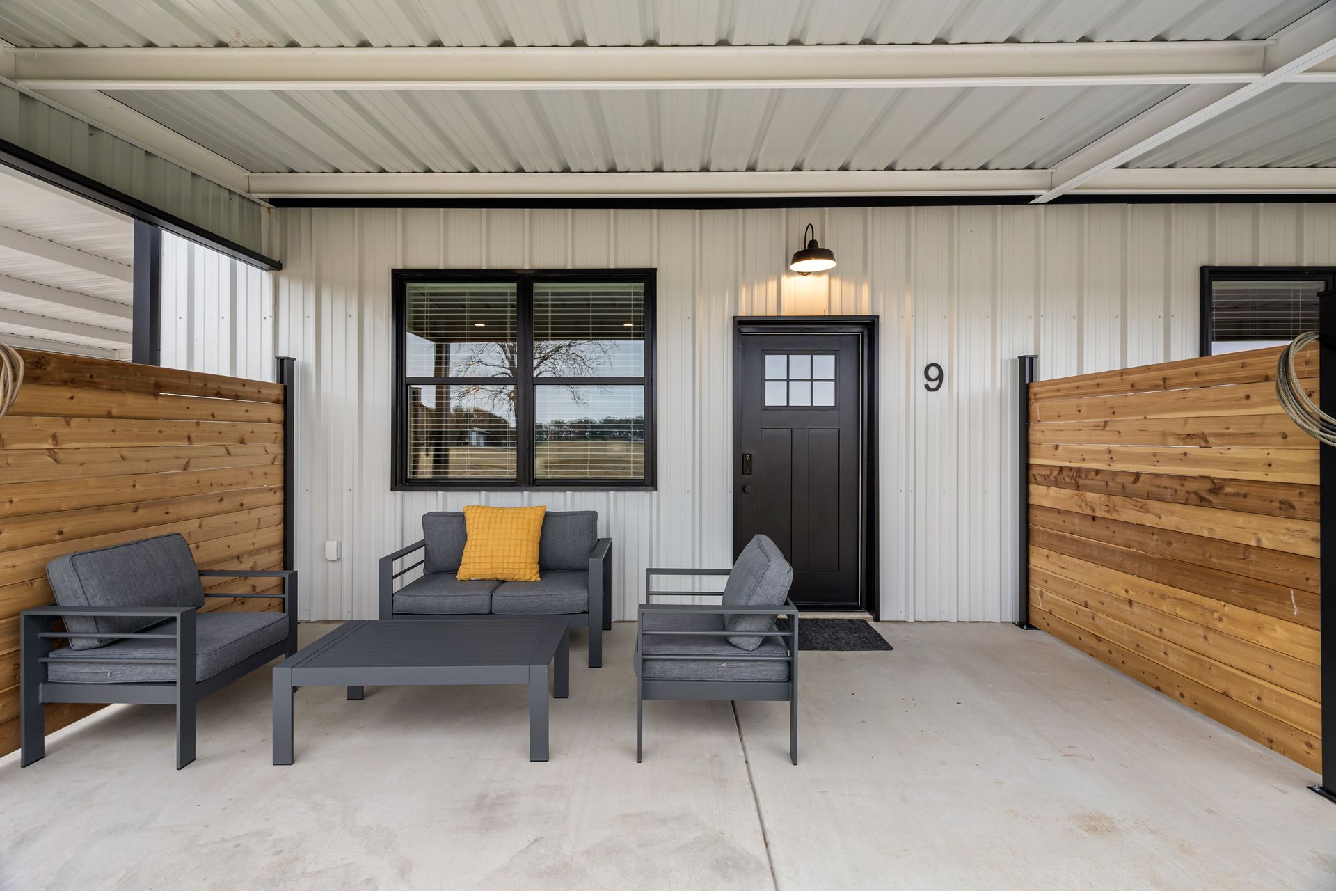 A patio with a couch , chairs , table and window.
