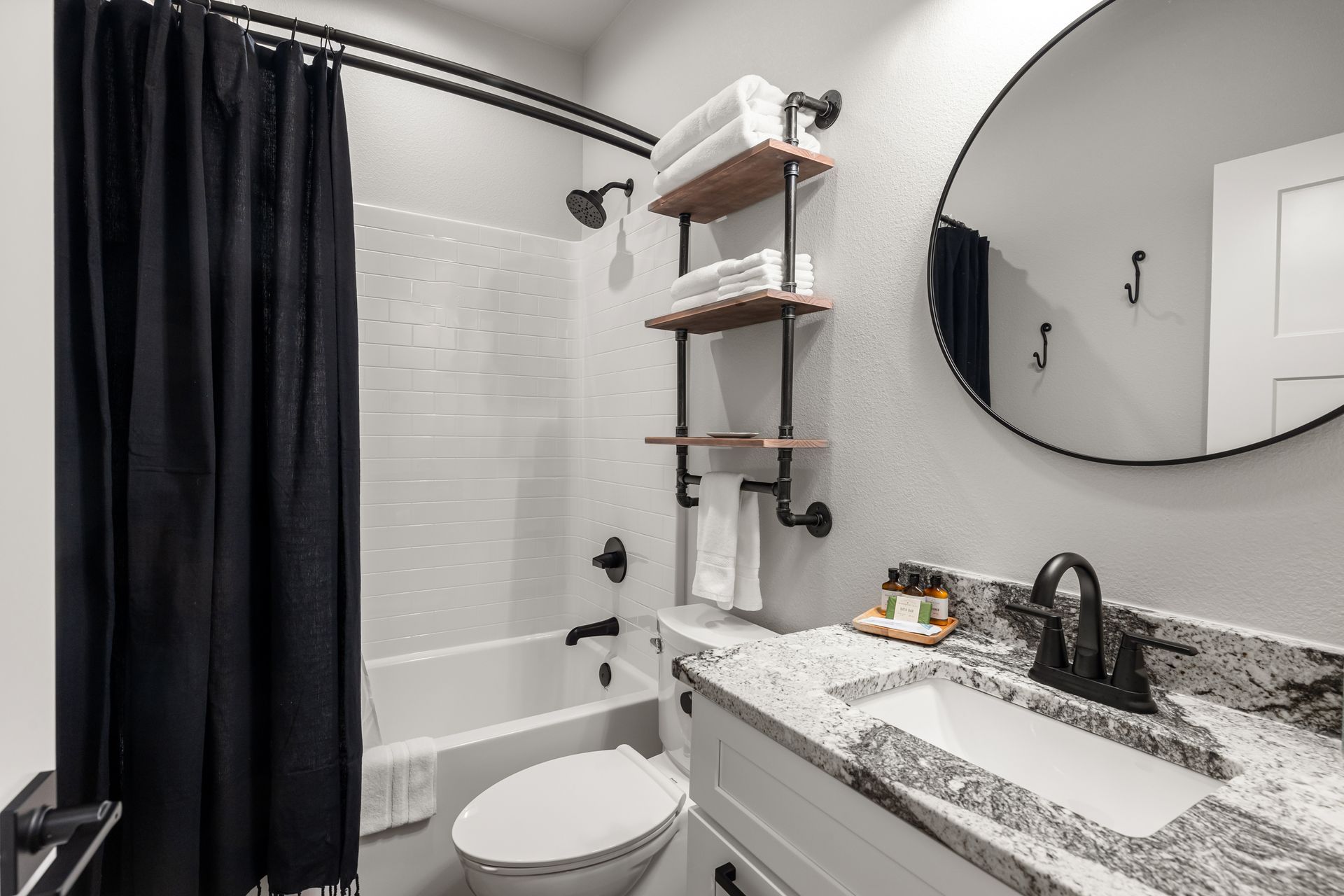 A bathroom with a toilet , sink , shower and mirror.