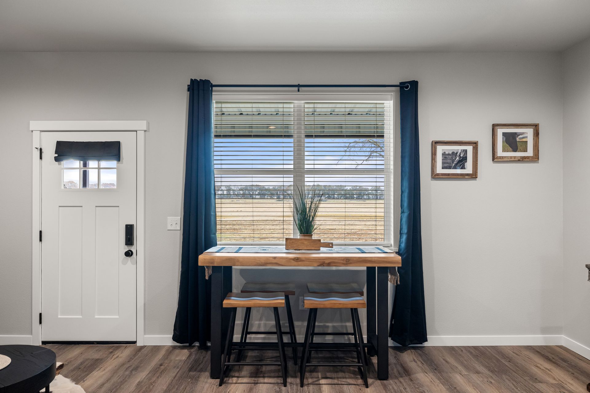 A living room with a table and stools in front of a window.