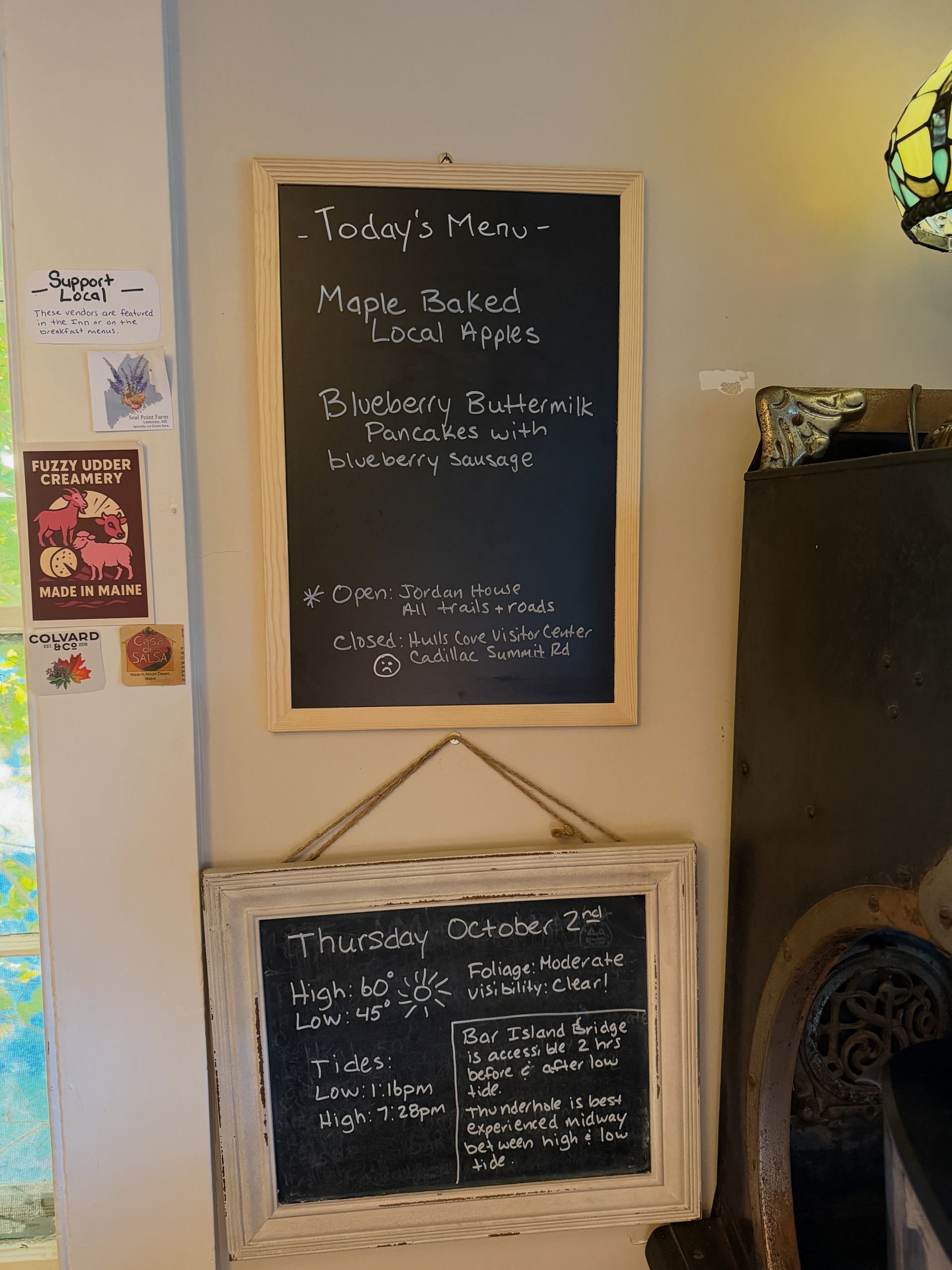 Two chalkboard menus hanging on a wall, listing daily specials in a cafe.