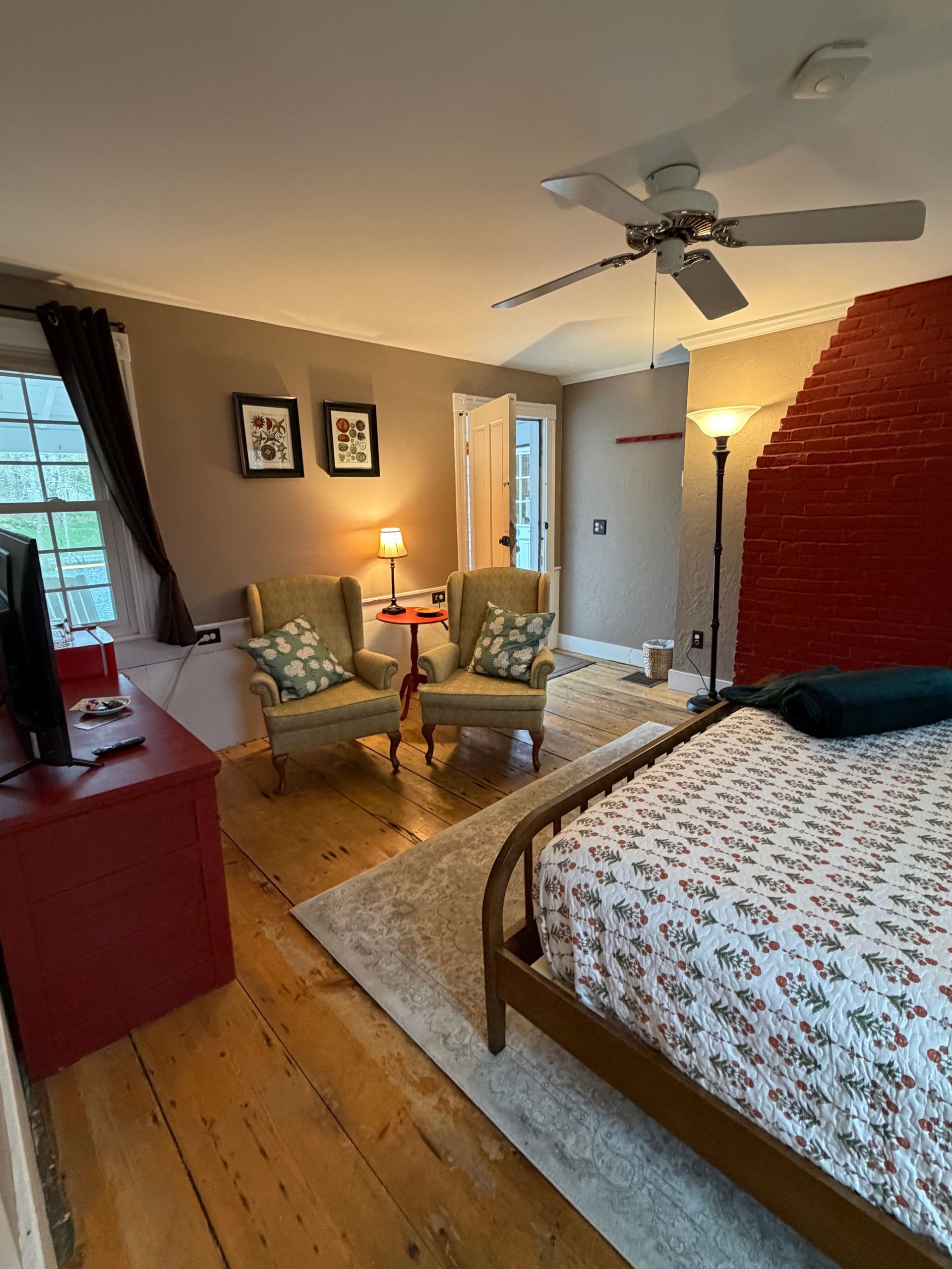 Cozy bedroom with king bed, armchairs, and ceiling fan in warm light