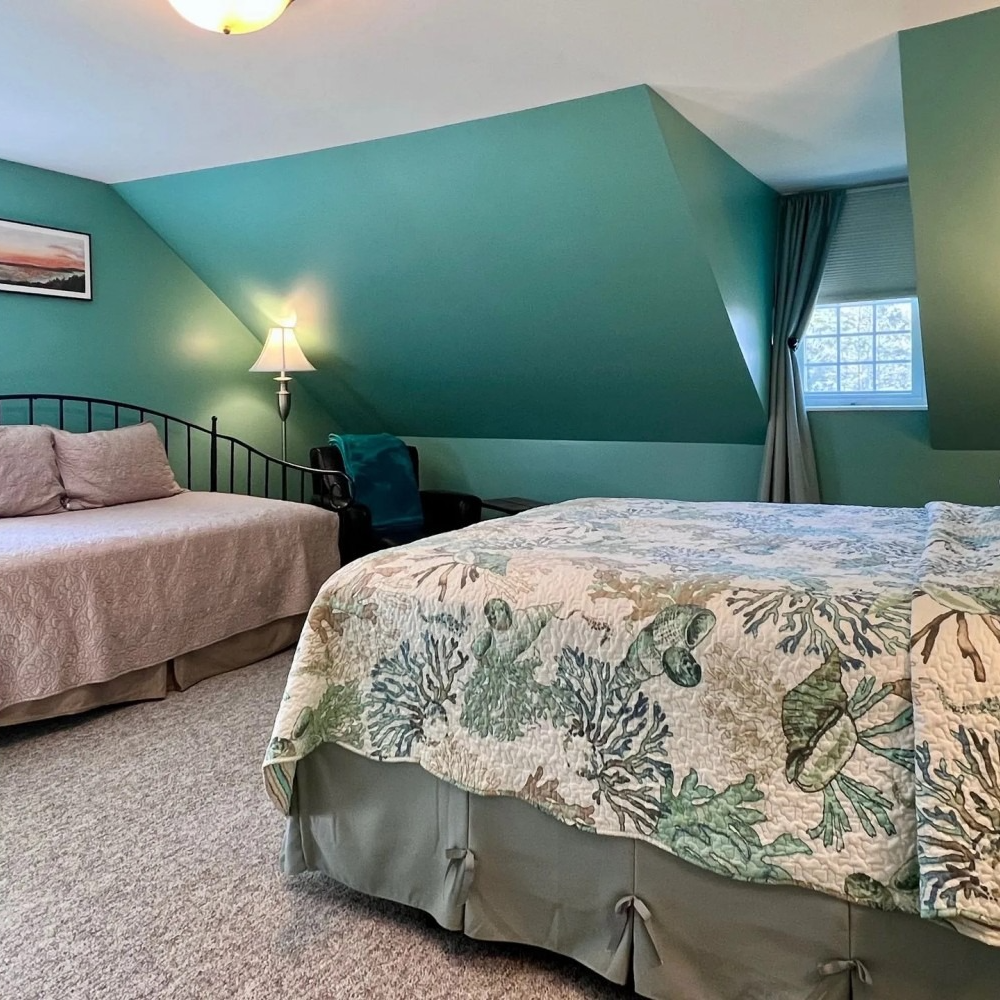 Bedroom with teal walls, a bed with floral quilt, and a daybed.