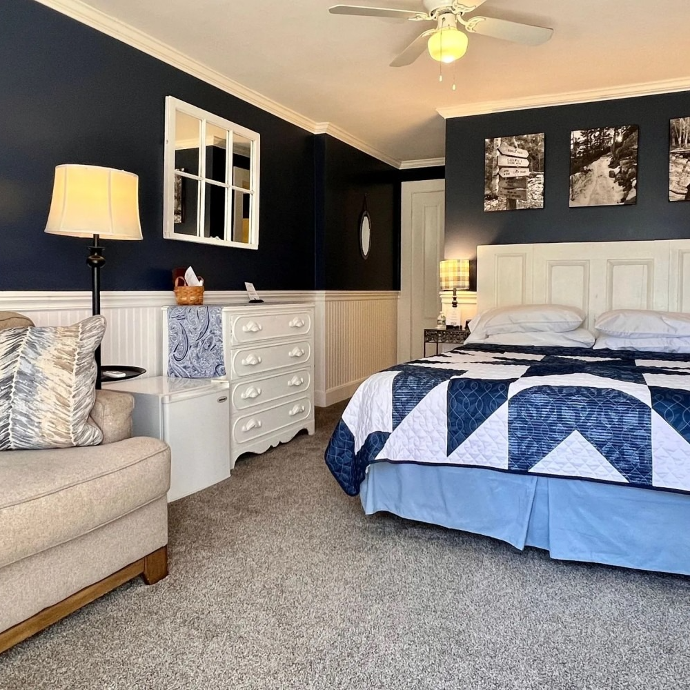 Bedroom with dark blue walls, white trim, and a bed with a blue and white quilt.