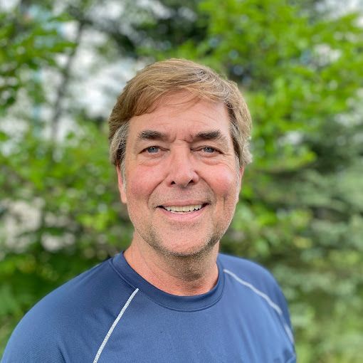 A man in a blue shirt is smiling for the camera.