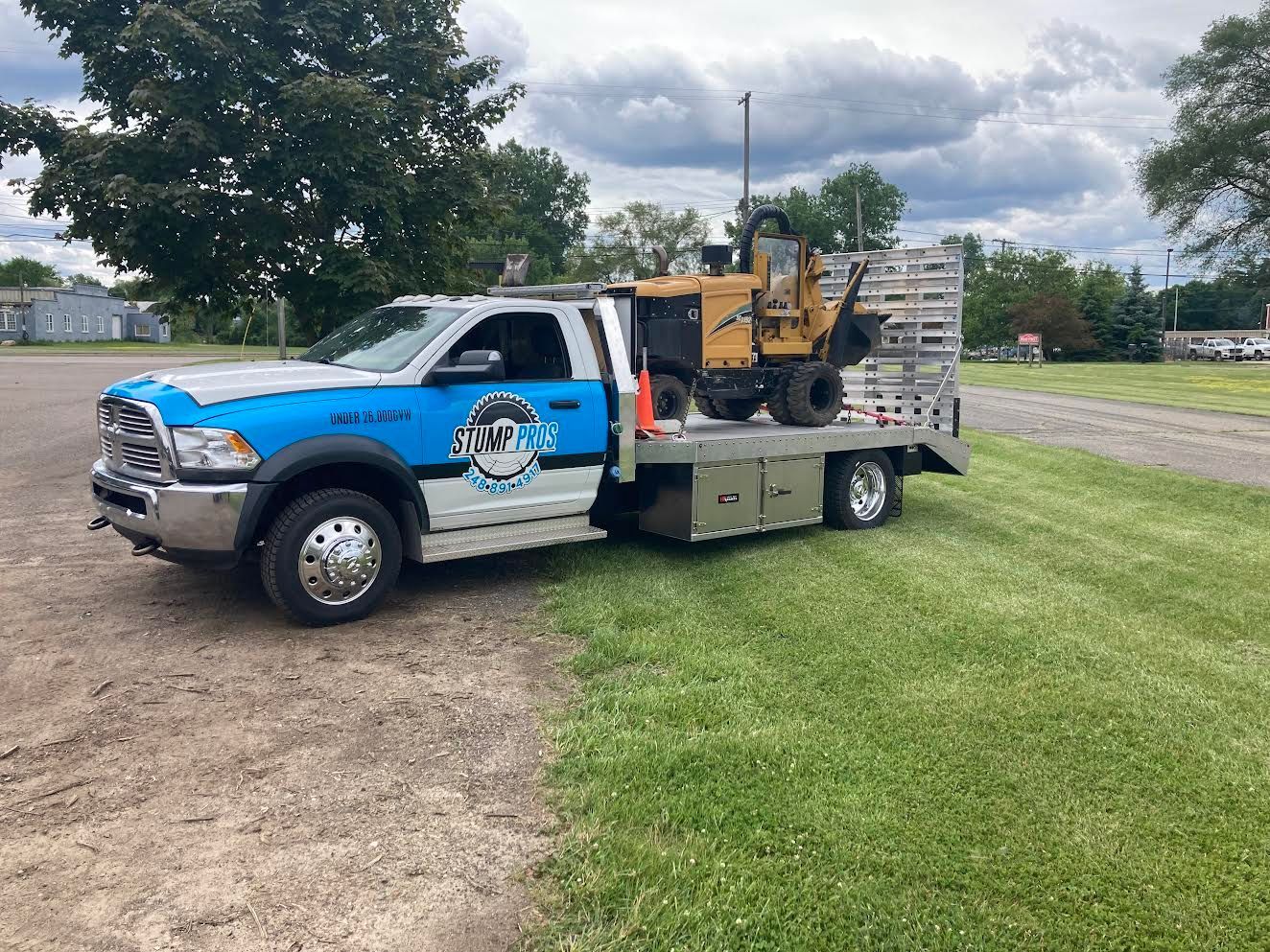 A tow truck with a bulldozer on the back is parked in a grassy field.