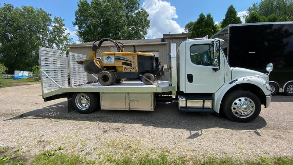 A tow truck is carrying a lawn mower on the back of it.