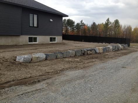 Un mur de pierre est en construction devant une maison.