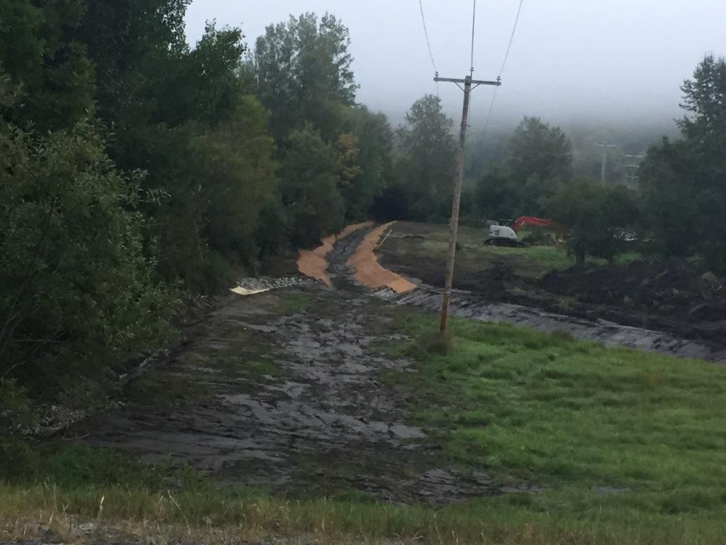 Une route boueuse traversant un champ avec des arbres et des lignes électriques