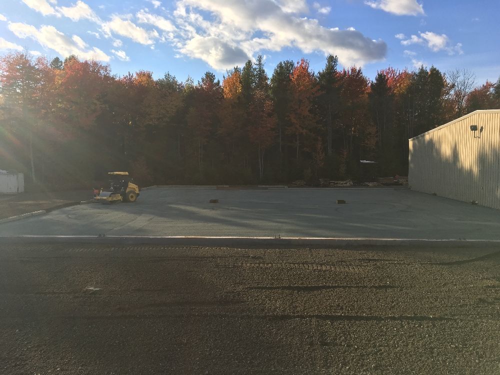 Une voiturette de golf est garée dans un parking avec des arbres en arrière-plan.