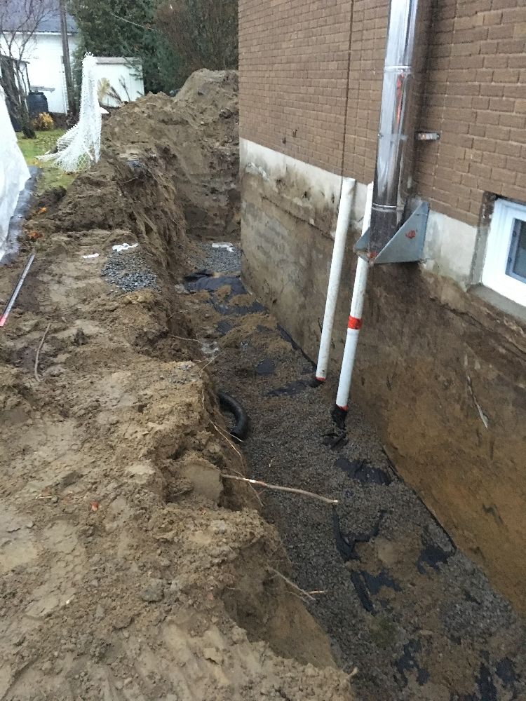 Un système de drainage est en cours d'installation sur le côté d'une maison.