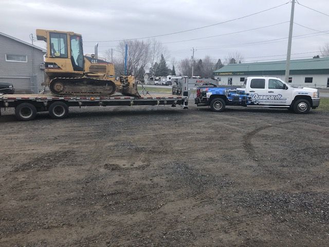 Un camion remorque un bulldozer sur une remorque à plateau.