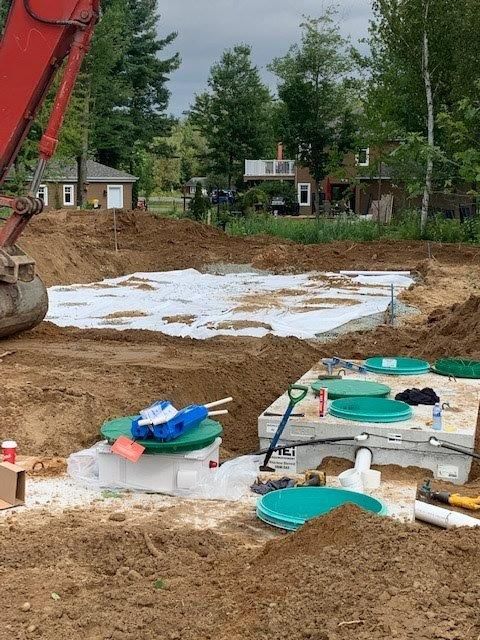 Une grande excavatrice rouge creuse dans la terre près d'une maison