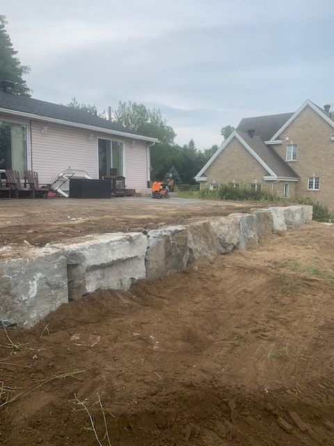 Une grande paroi rocheuse est en construction devant une maison.
