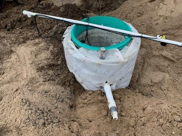 Un seau repose dans la terre à côté d'un tuyau.