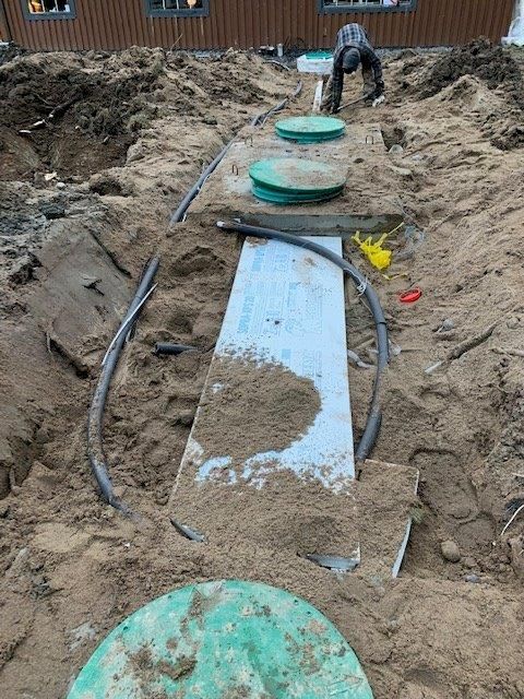 Un homme travaille sur une fosse septique dans la terre.