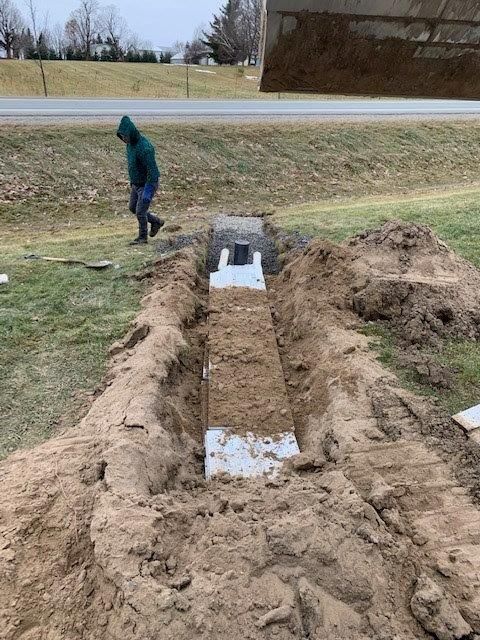 Un homme vêtu d'un sweat à capuche vert creuse un trou dans le sol.