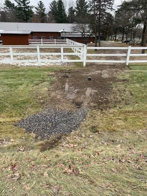 Il y a une clôture blanche au milieu d'un champ herbeux.