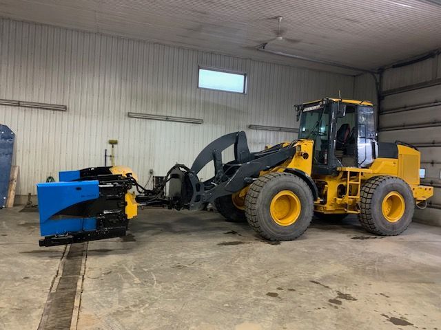 Un tracteur jaune et noir est garé dans un garage.