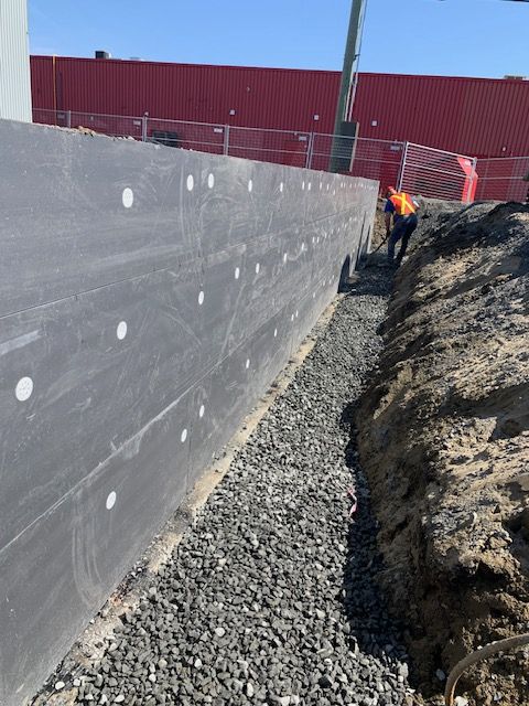 Un homme creuse un trou dans le sol à côté d'un mur.
