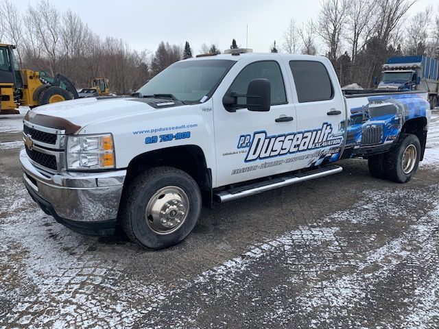 Un camion blanc est garé dans un parking enneigé.