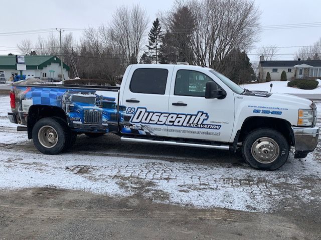 Un camion blanc avec le mot dusseault sur le côté est garé dans la neige.