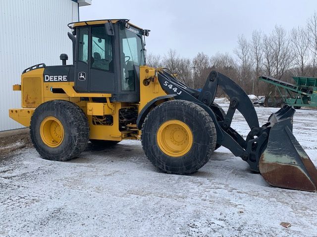 Une chargeuse sur pneus jaune et noire est garée dans la neige.
