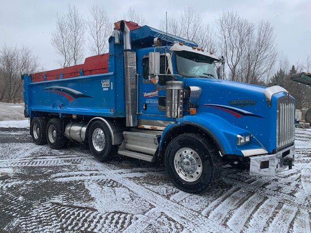 Un camion-benne bleu est garé dans un champ enneigé.