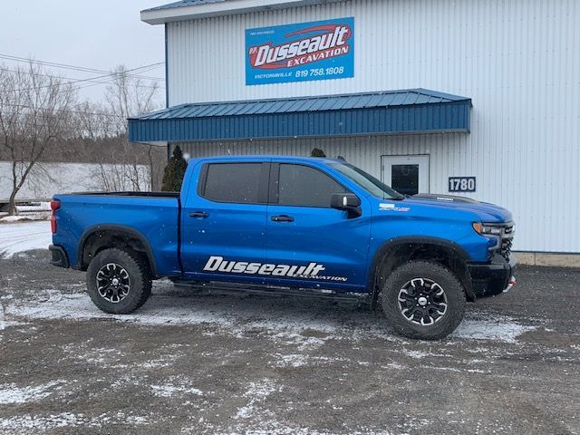 Un camion bleu est garé devant un immeuble.