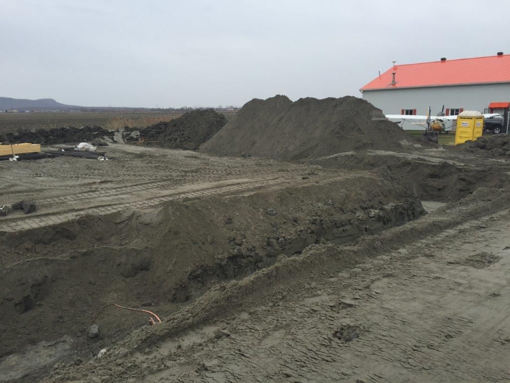 Un gros tas de terre se trouve devant un bâtiment au toit rouge
