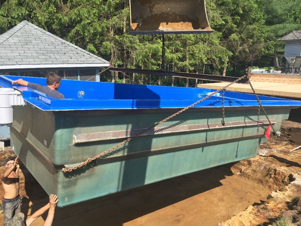 Une piscine bleue et verte est en construction dans une cour