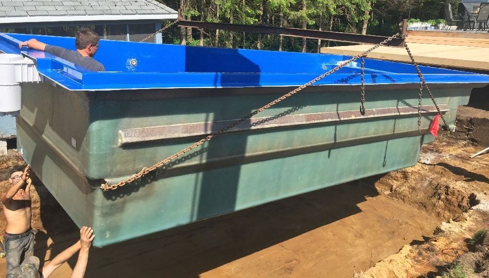 Une grande piscine bleue et verte est en train d'être creusée dans le sol.