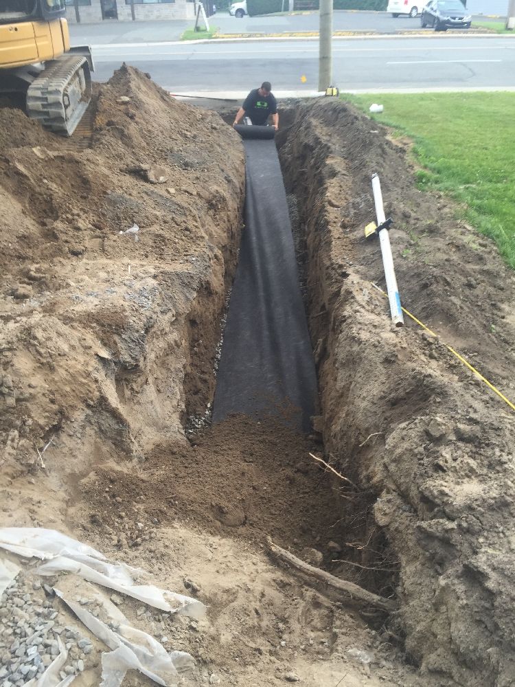 Un homme travaille dans une tranchée à côté d'une route.