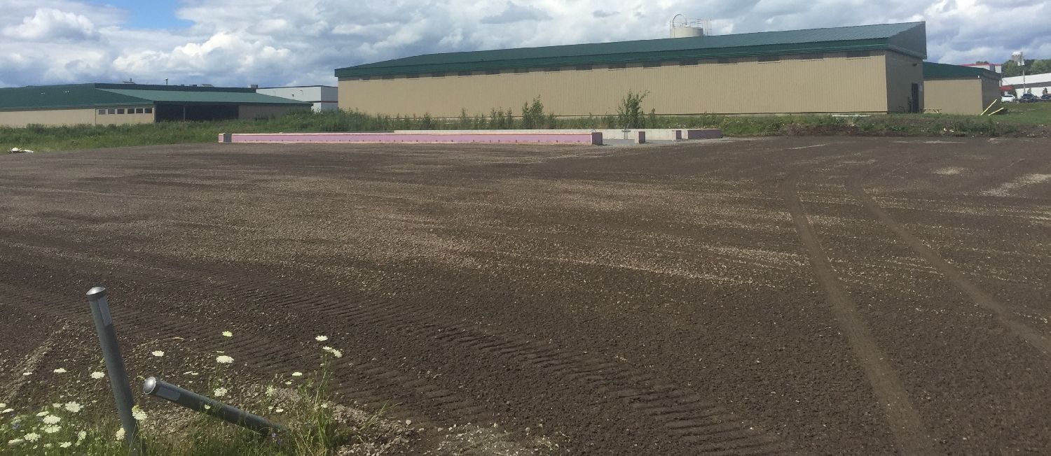 Un grand bâtiment se trouve au milieu d'un champ de terre.